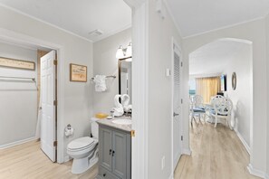 A bathroom with a toilet, sink, and vanity, a dining area with a table and chairs, and a hallway leading to another room.