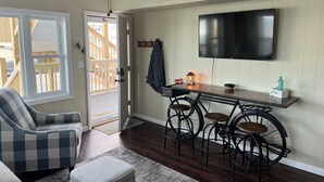 A living room with a sofa, ottoman, and a dining area with a table and chairs. - 1st Floor Direct Bayfront 1 bedroom Updated Condo with pool overlooking the bay! (Ocean City)