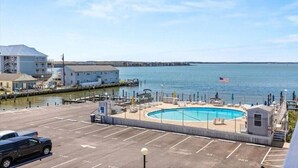A waterfront hotel with a swimming pool, parking area, and a view of the sea. - 1st Floor Direct Bayfront 1 bedroom Updated Condo with pool overlooking the bay! (Ocean City)
