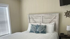 A bed with a wooden headboard, white bedding, and two decorative pillows. - 1st Floor Direct Bayfront 1 bedroom Updated Condo with pool overlooking the bay! (Ocean City)