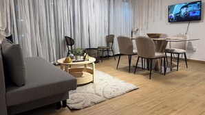 Una sala de estar moderna con un sofá gris, una mesa de centro redonda y un comedor con sillas y una mesa.
