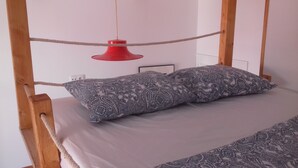 Ein Bett mit einem gemusterten Kopfkissen und einer roten Pendelleuchte.