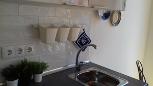 Eine Küche mit einem Edelstahl-Spülbecken, einer weißen Fliesenrückwand und einem blauen Dekotuch an der Wand.