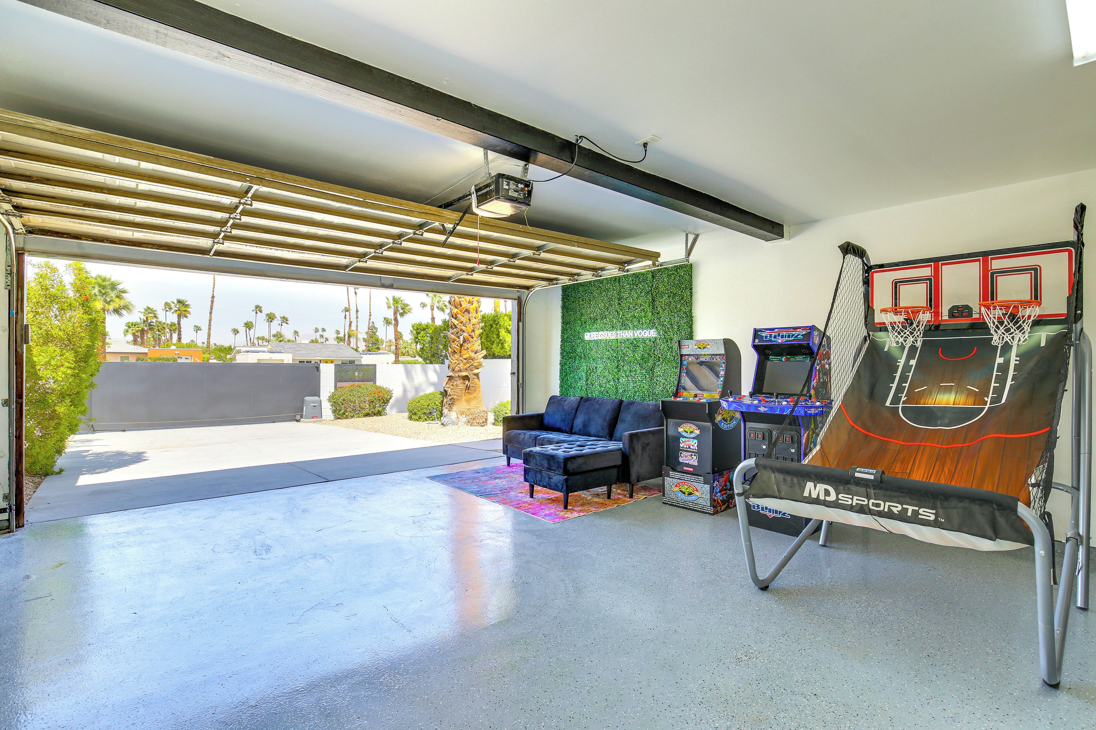 An indoor recreational area with a basketball hoop, a couch, and arcade games.