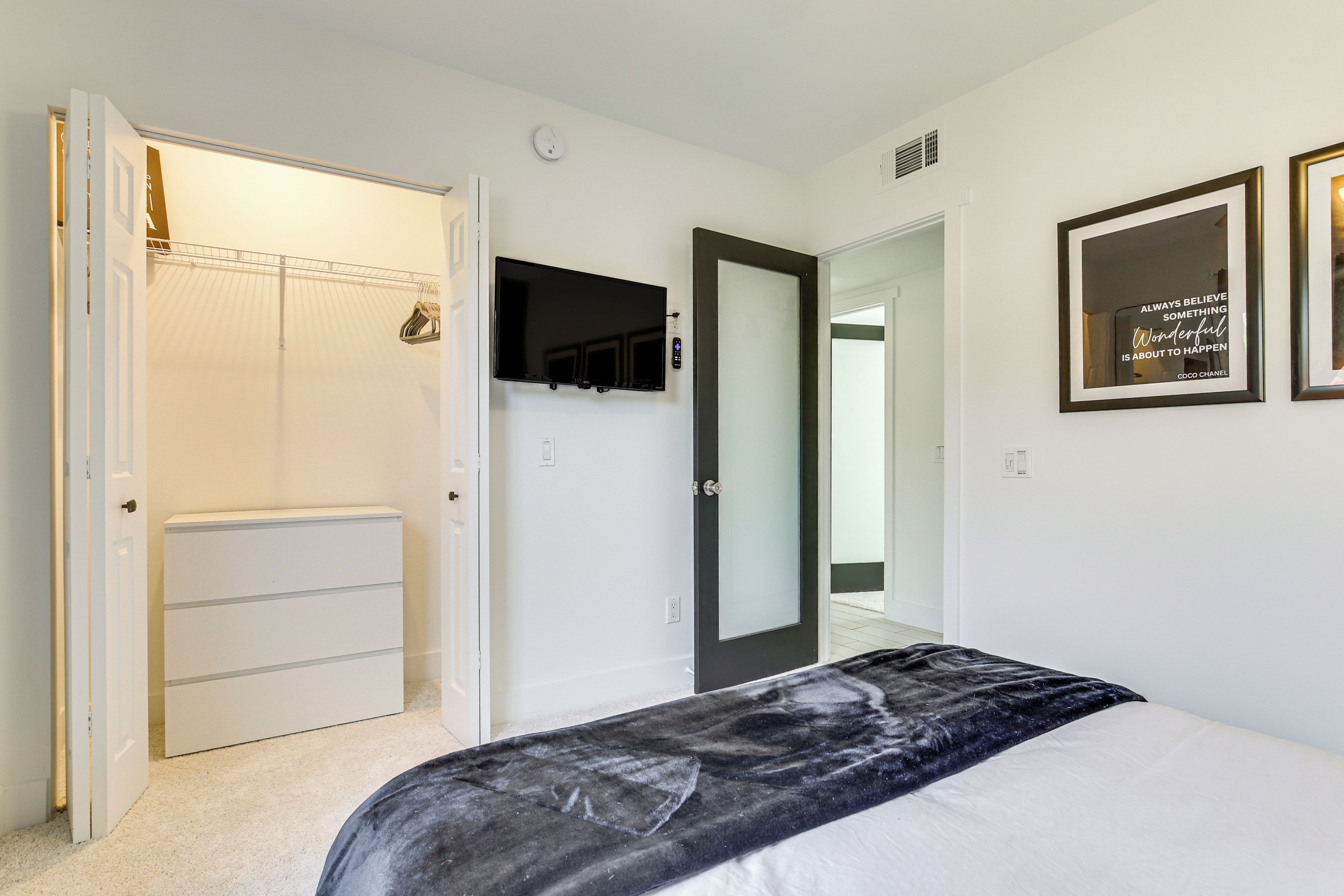 A bedroom with a bed, a wardrobe, a television, and a mirror.