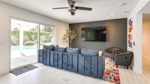 A modern living room with a sofa, a ceiling fan, a flat-screen TV, and a colorful rug. - Mtn Views & Outdoor Oasis: Palm Springs Getaway (Palm Springs)