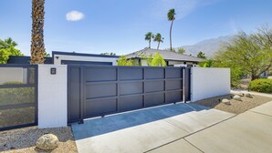 A modern garage with a large black door, a concrete driveway, and a white wall. - Mtn Views & Outdoor Oasis: Palm Springs Getaway (Palm Springs)