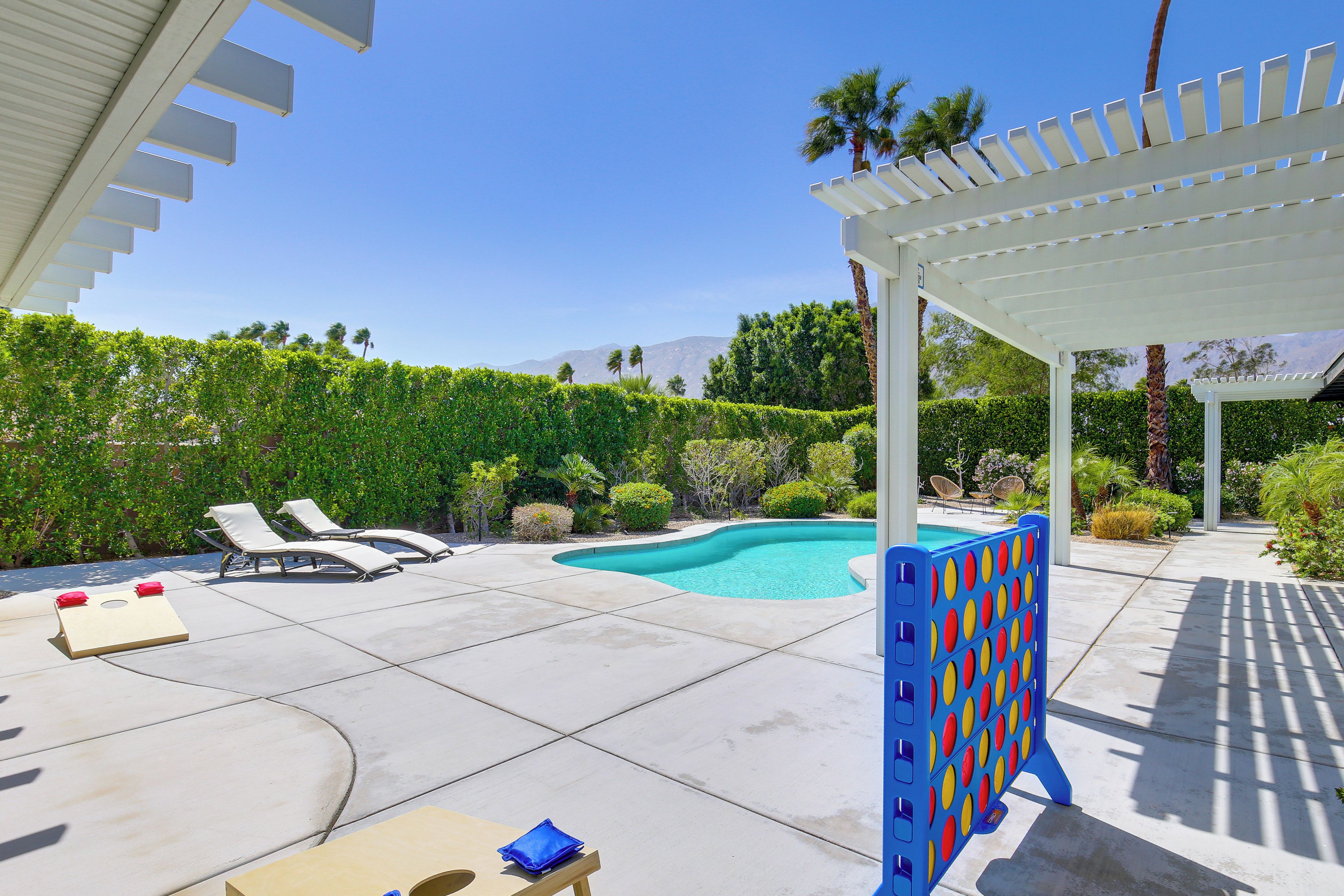 A pool area with lounge chairs, a table, and a pergola.
