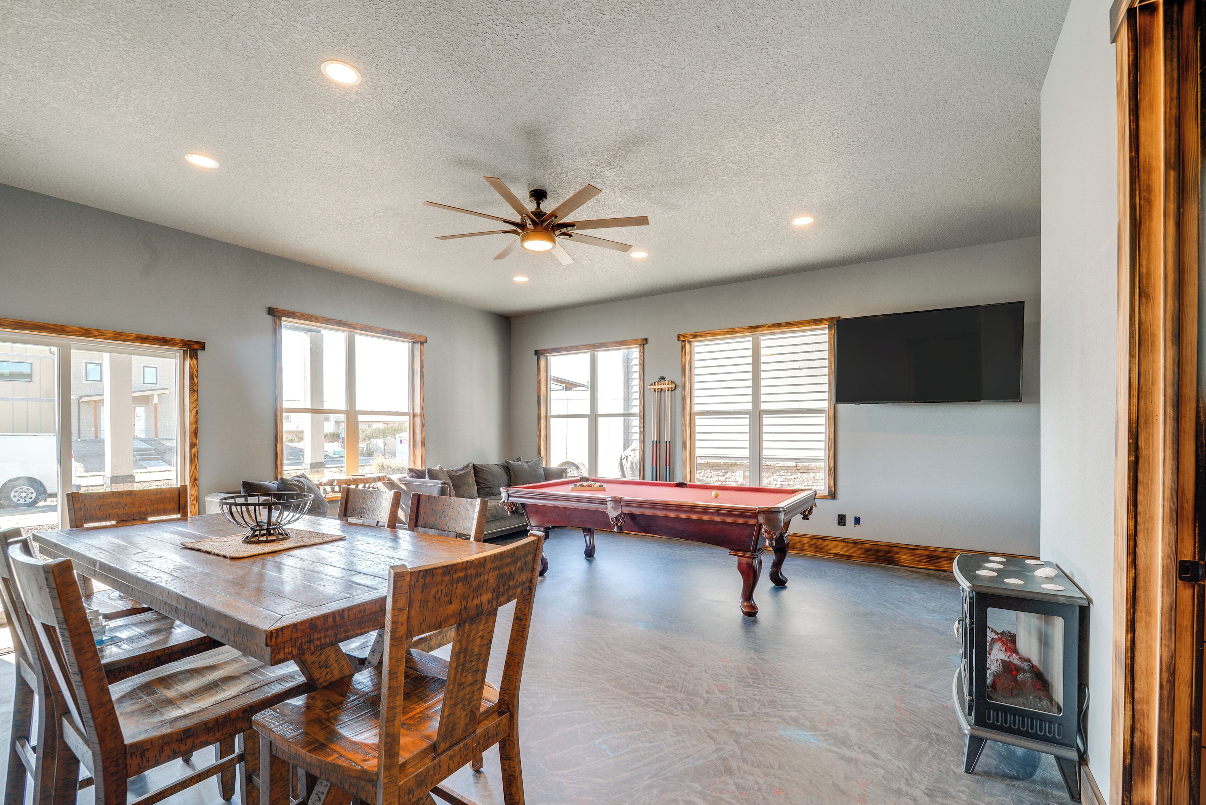 A spacious room with a pool table, wooden dining table, and chairs.