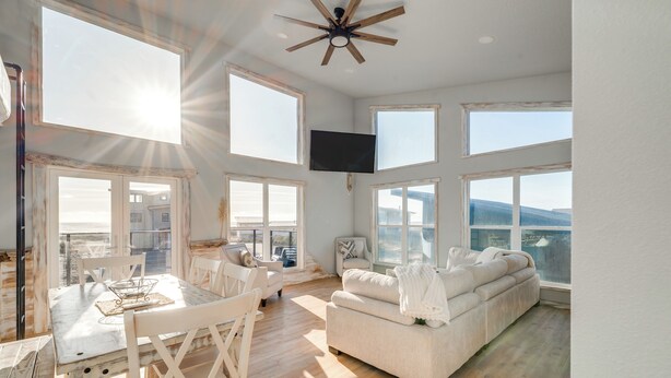 Un salon spacieux avec un plafond haut, de grandes fenêtres et un ventilateur de plafond.