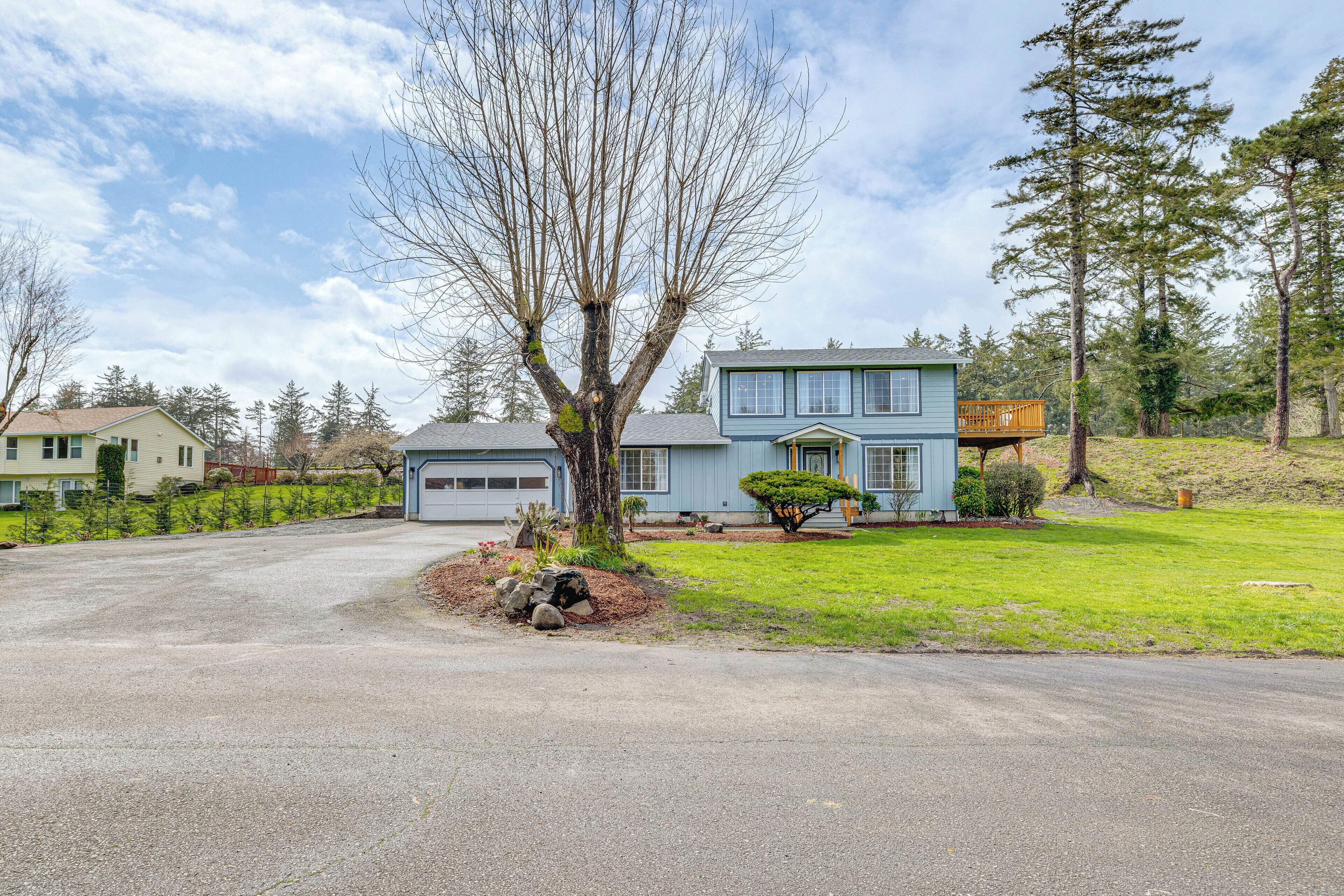 A two-story house with a garage, a tree in the front yard, and a small deck on the second floor.