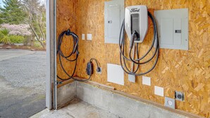 An electrical panel with a Ford charger and a power outlet on a wooden wall. - 3 Mi to Beach: Oregon North Coast Retreat (Warrenton)