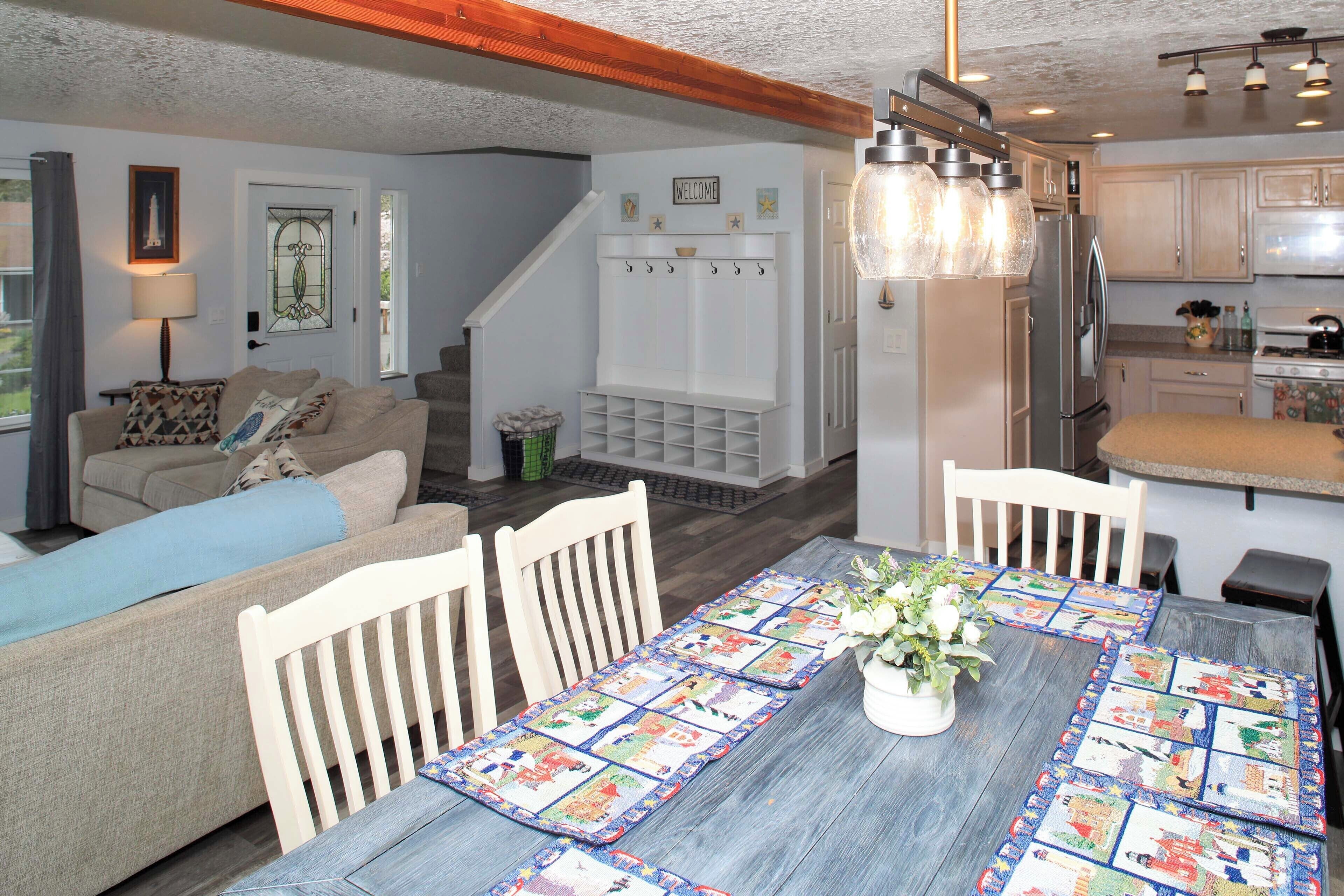 A cozy living room with a sofa, a dining table with a quilt, and a kitchen area with cabinets and appliances.