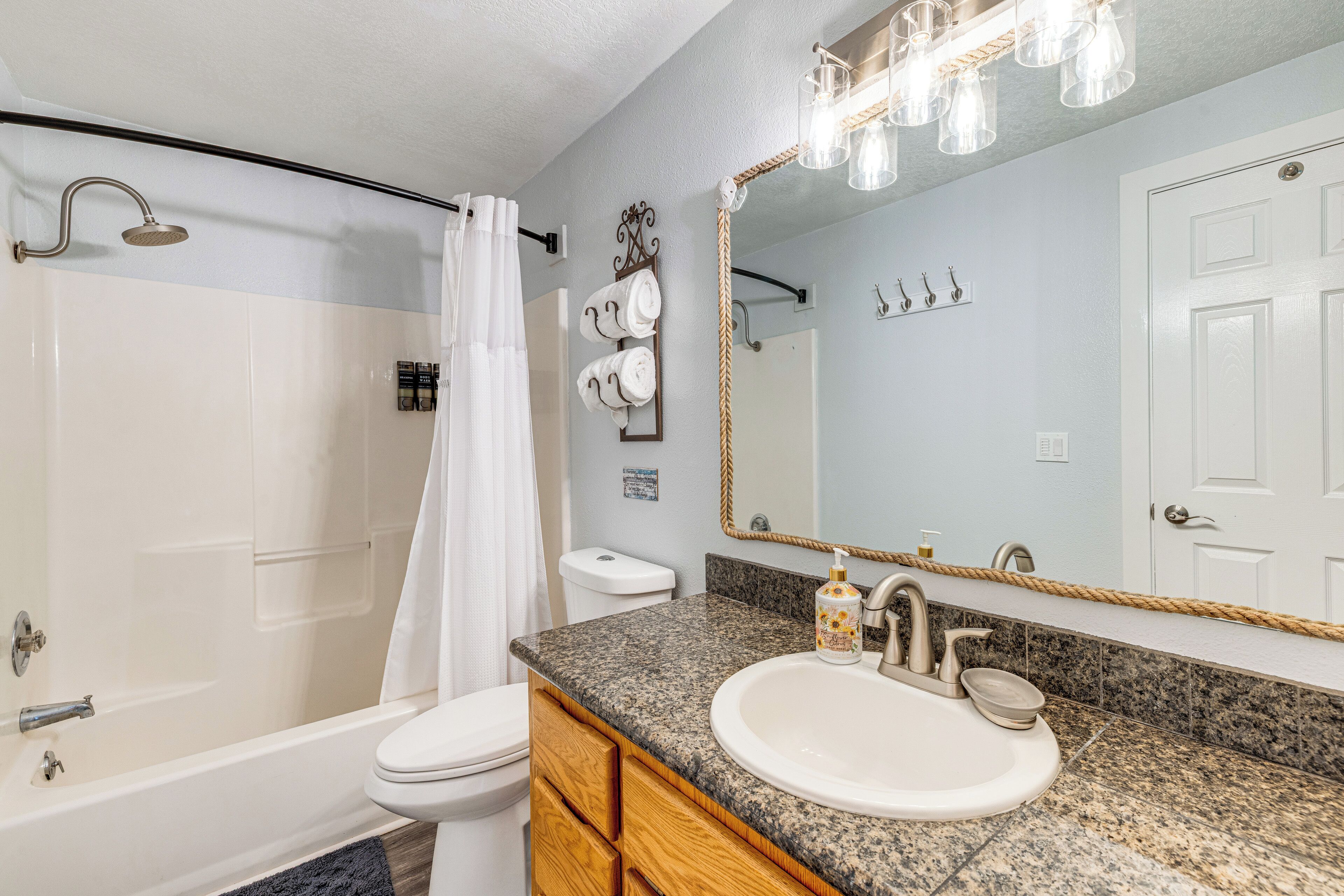 A bathroom with a shower, toilet, sink, and vanity.