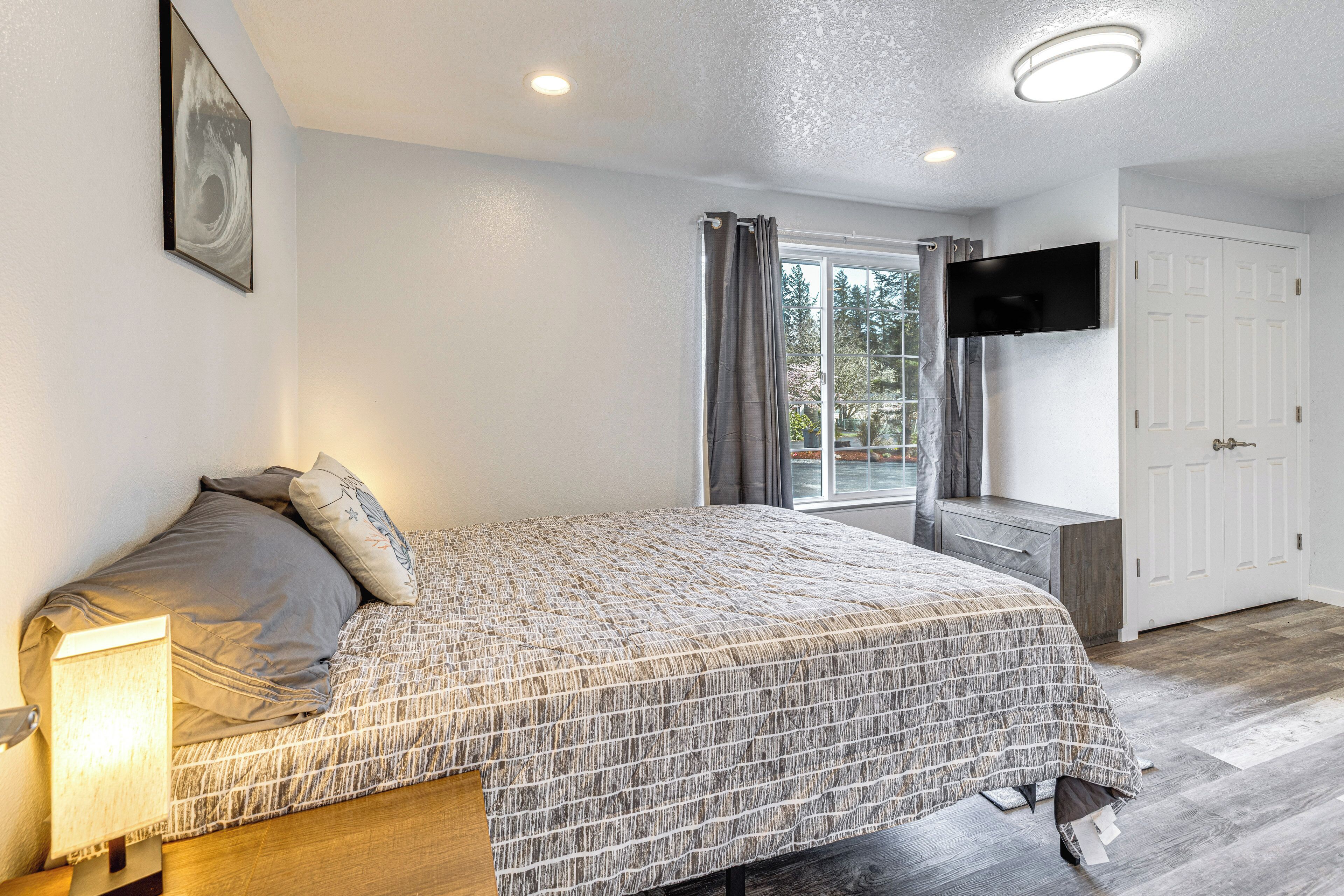 A bedroom with a bed, bedside table, and a TV mounted on the wall.