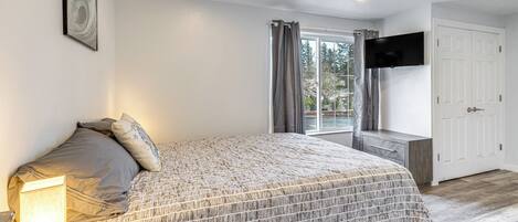 A bedroom with a bed, bedside table, and a TV mounted on the wall.