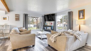 A living room with two beige sofas, a coffee table, and a flat-screen TV. - 3 Mi to Beach: Oregon North Coast Retreat (Warrenton)