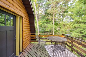 A wooden cabin with a deck, a round table, and two chairs.