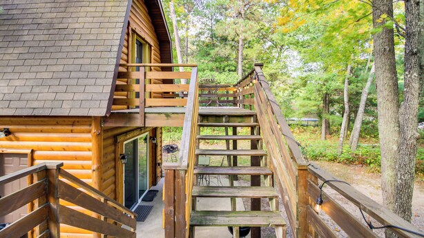 A wooden cabin with a staircase leading to a deck, surrounded by trees. - Fish, Hike & More: Cozy Brainerd Cabin (Brainerd)