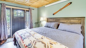 A bedroom with a large bed, a wooden ceiling, and a door leading outside. - Fish, Hike & More: Cozy Brainerd Cabin (Brainerd)