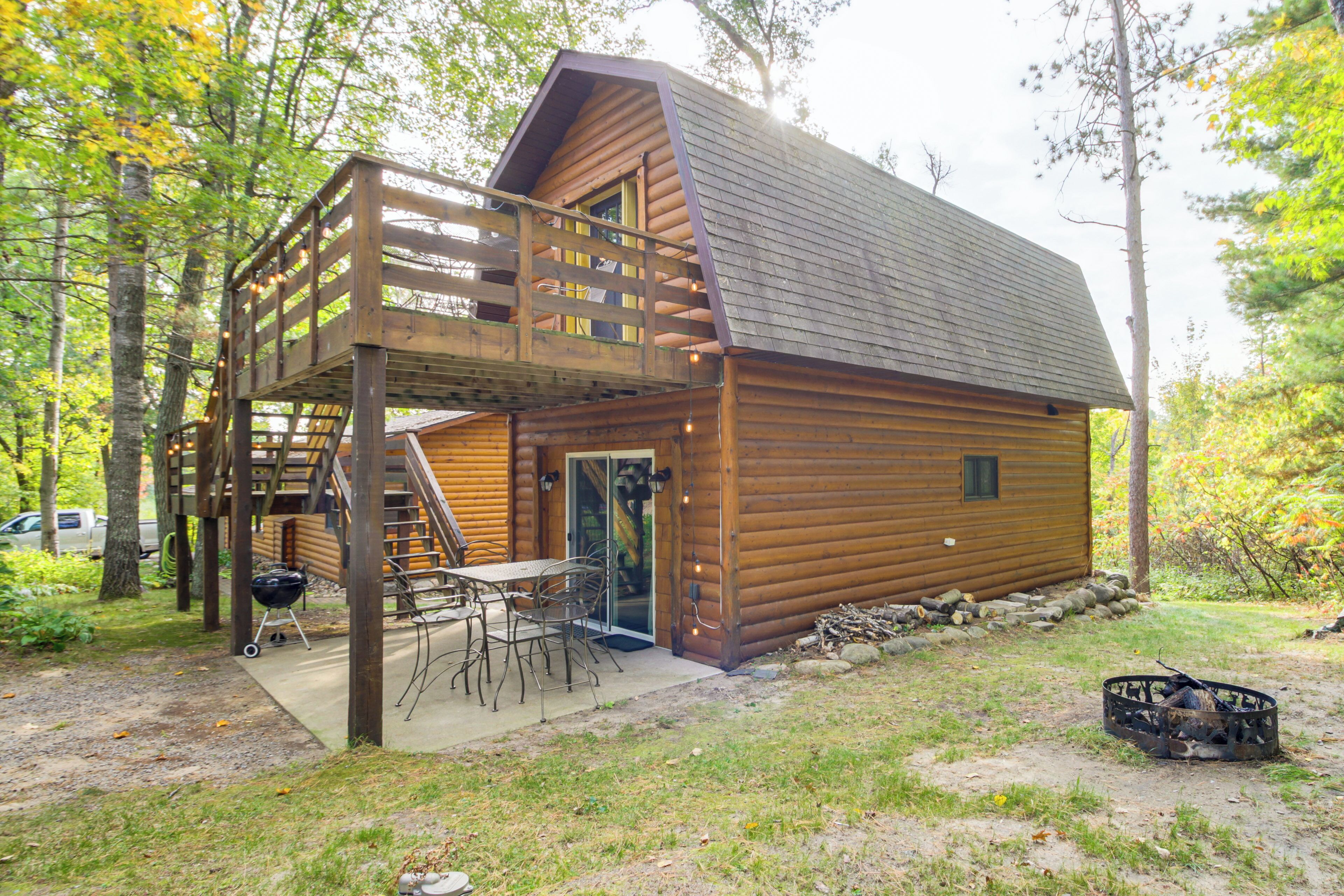 Eine Blockhütte mit einer Terrasse, Sitzgelegenheiten im Freien und einer Feuerstelle.