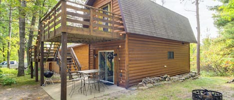 Eine Blockhütte mit einer Terrasse, Sitzgelegenheiten im Freien und einer Feuerstelle.