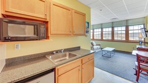 A kitchen with wooden cabinets, a granite countertop, a built-in microwave, and a sink.