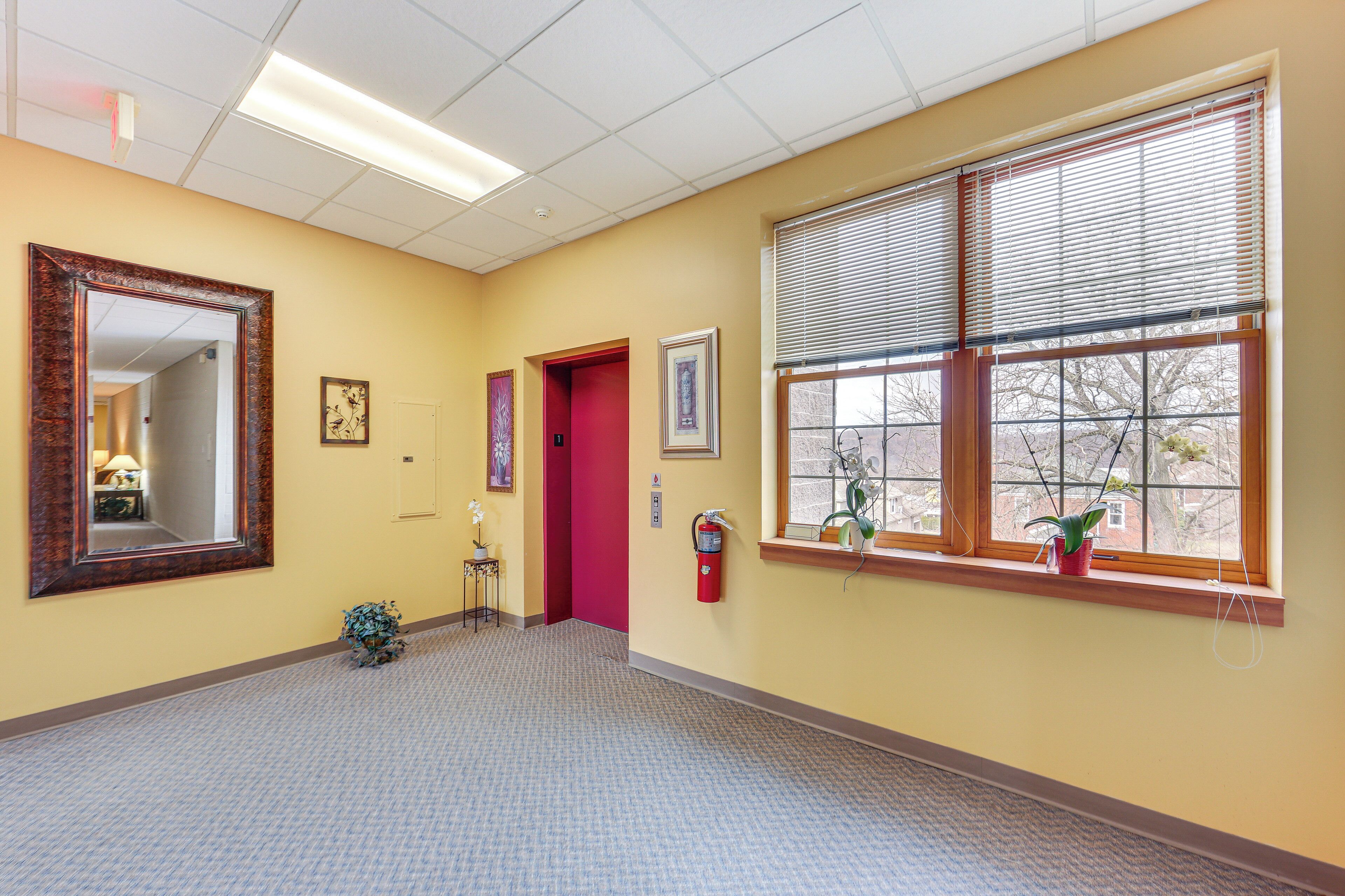 A hallway with a fire extinguisher, a mirror, and a door.
