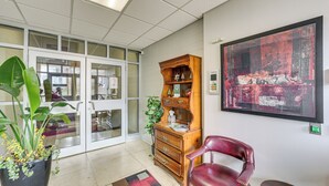 A room with a large window, a wooden cabinet, a red chair, and a painting on the wall.