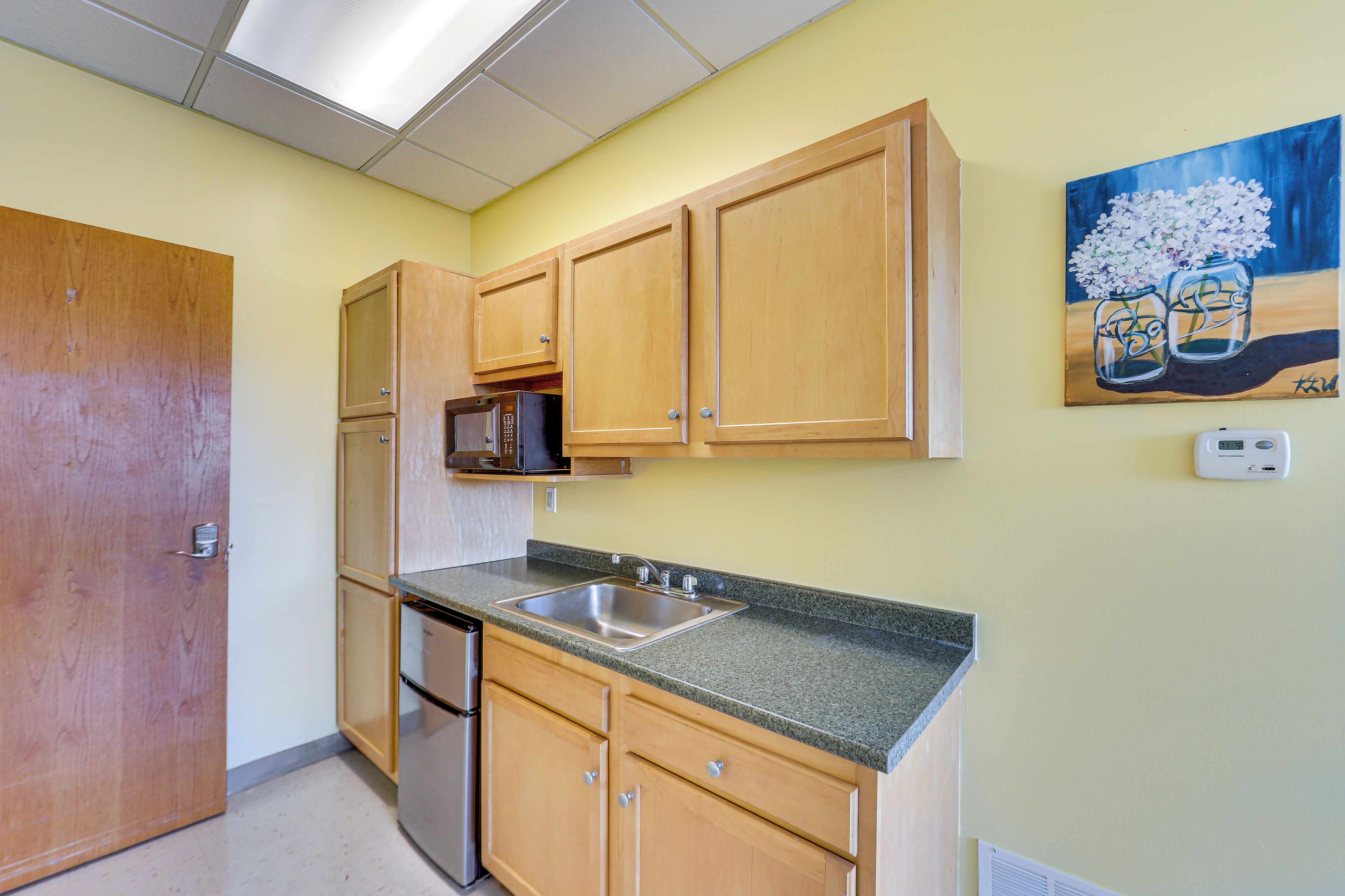 A kitchen with wooden cabinets, a stainless steel sink, and a microwave.