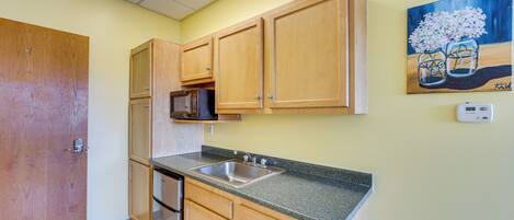 A kitchen with wooden cabinets, a stainless steel sink, and a microwave.
