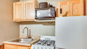 A kitchen with wooden cabinets, a microwave, a sink, and a stove. - 5 Mi to Rice Lake State Park: Lake Mills Studio (Lake Mills)
