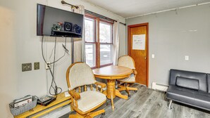 A room with a wooden dining table, two chairs, a television mounted on the wall, and a black leather couch. - 5 Mi to Rice Lake State Park: Lake Mills Studio (Lake Mills)