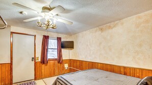 A bedroom with a bed, a ceiling fan, a television, and wooden paneling on the walls. - 5 Mi to Rice Lake State Park: Lake Mills Studio (Lake Mills)