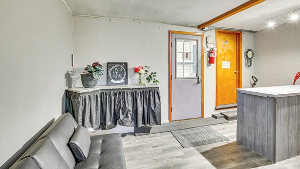 A compact living space with a sofa, a small table with decorative items, a wooden counter, and a door with a fire extinguisher. - 5 Mi to Rice Lake State Park: Lake Mills Studio (Lake Mills)