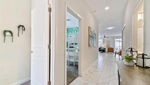 A spacious hallway with a white door, a white bench, and a potted plant.