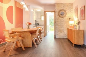 A modern kitchen with a stone wall, wooden furniture, and a view to the outside.
