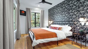 Une chambre à coucher avec un lit, un ventilateur de plafond, une table de chevet et une fenêtre avec des rideaux.