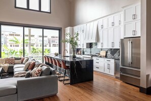 Een moderne keuken met witte kastjes, een groot eiland en een roestvrijstalen koelkast.