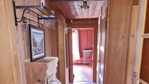 Un couloir en bois avec un radiateur, une porte dotée d’une poignée et un sol carrelé.