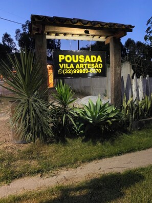 Placa com o nome 'POUSADA VILA ARTESÃO' e um número de contato.