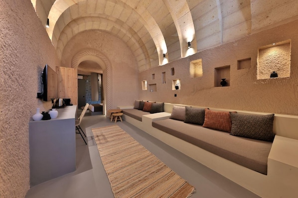 Un intérieur moderne avec un long canapé incurvé, une petite table et un téléviseur fixé au mur.