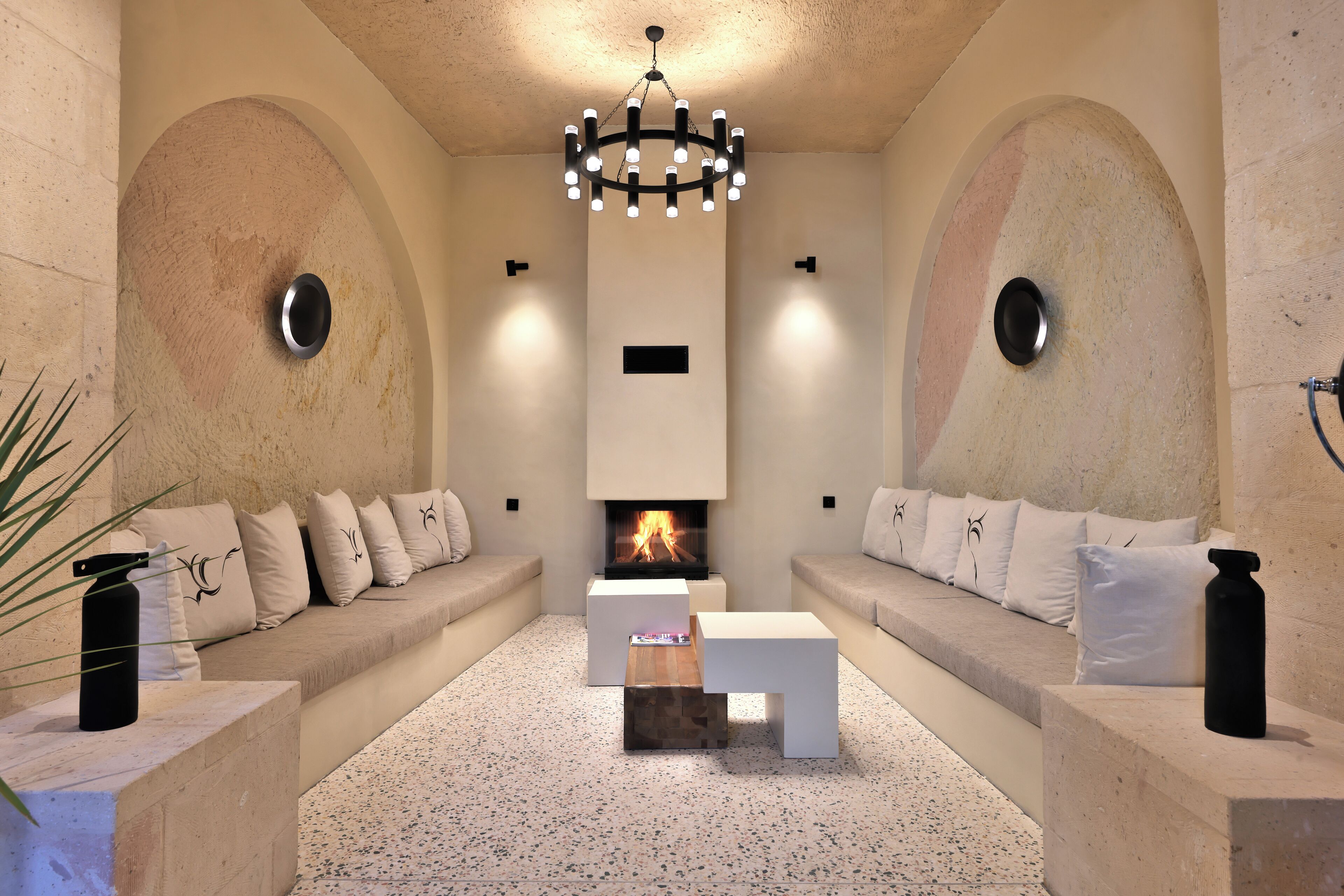 A modern living room with a fireplace, two sofas, a coffee table, and a chandelier.