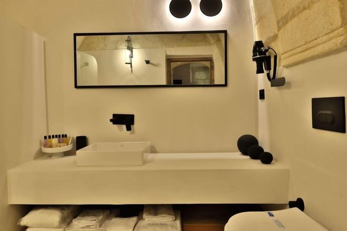 Une salle de bain moderne avec un lavabo blanc, un grand miroir et un porte-serviettes.