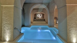 Un espace spa doté d’une piscine centrale, d’un coin salon et d’un mur à motifs texturés, orné de motifs circulaires.