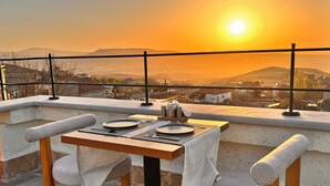 A table set for two with a view of the sunset over a mountainous landscape. - Simurg Cave House (Urgup)