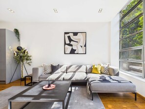 Una sala de estar moderna con un sofá seccional, una mesa de centro y un ventanal con vista a la vegetación.