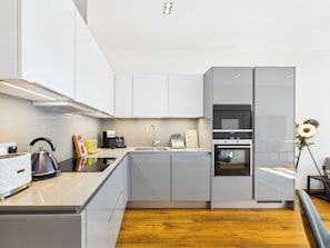 Una cocina moderna con horno empotrado, cafetera y hervidor sobre la encimera.