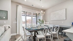 A modern dining area with a large table, white chairs, and a chandelier. - 52-53 | Family reunion home! 2 pools, 2 hot tubs (Santa Clara)