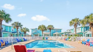 A swimming pool with lounge chairs and palm trees. - Blessed Getaway Stay for 10! (Port Aransas)